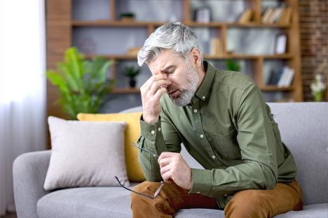 muškarac srednjih godina se drži za glavu kao da oseća umor