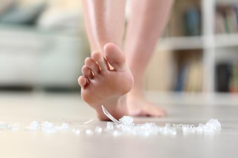 bosonoga žena gazi na razbijeno staklo na podu