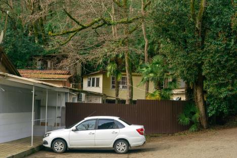 Beli auto parkiran ispred dvorišta kuće