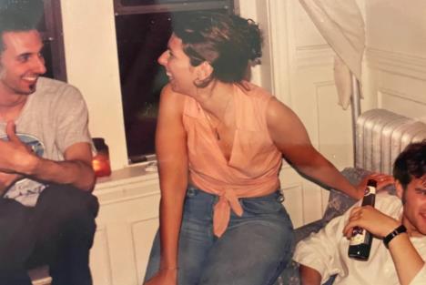 Žena sedi na naslonu stolice pored tadašnjeg dečka dok se u pozadini nalazi muškarac koji će kasnije postati njen suprug