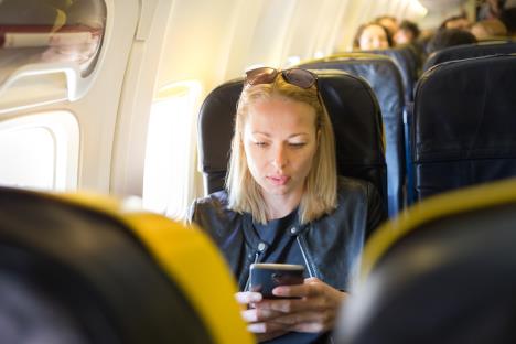 žena u avionu pali avionski režim na telefonu
