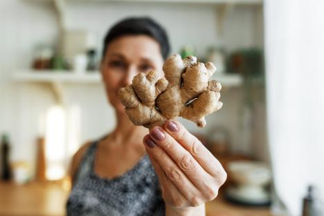 žena drži koren đumbira i pokazuje ka kameri