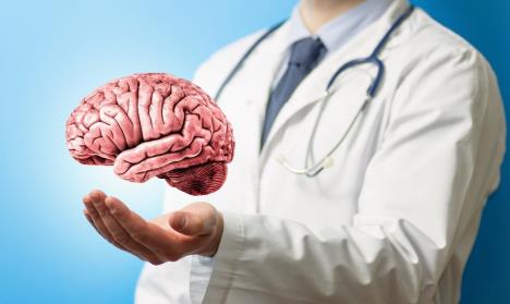 doktor u belom mantilu drži model mozga koji levitira iznad opužene ruke