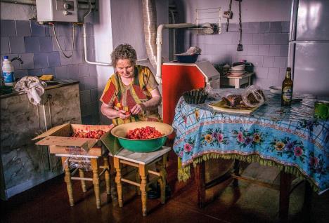 Žena secka jagode u lavoru u kuhinji