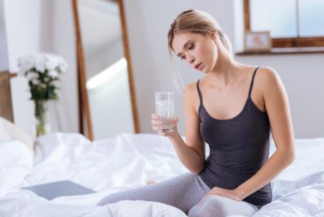 mlada žena u krevetu razmišla da li da popije čašu vode koja je odstojala preko noći