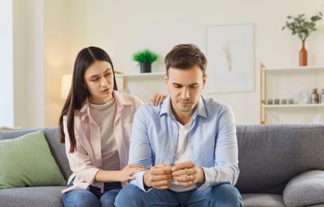 Devojka teši dečka, drži mu ruku na ramenu