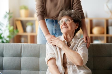 starija žena sedi na kauču i njena odrasla ćerka koja još pruža podršku