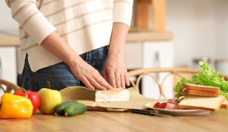 žena uvija sir u papir za čuvanje hrane na stolu