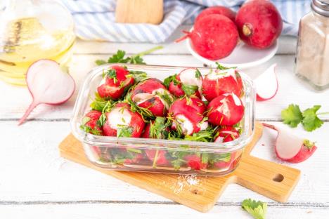 salata od rotkvica servirana u staklenoj činijici na drvenoj dasci