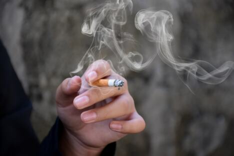 ruka mlade žene koja drži zapaljenu cigaretu