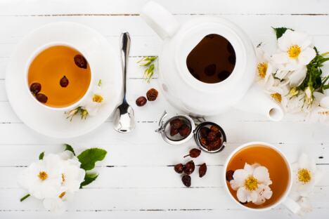 čaj od šipurka serviran u dve šoljice uz čajnik i sveže svetove šipurka