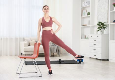 mlada žena vežba pored stolice vežbu za kukove