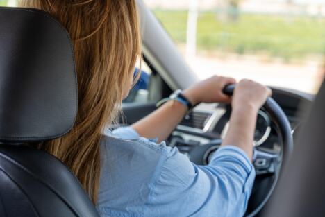 Žena u plavoj košulji vozi auto