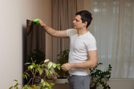 Muškarac briše prašinu sa televizora