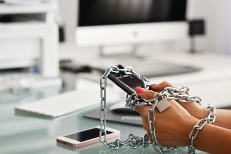 ruke žene okovane lancima drže mobilni telefon, koncept zavisnost od telefona