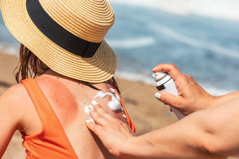 Majka nanosi kremu detetu na plaži