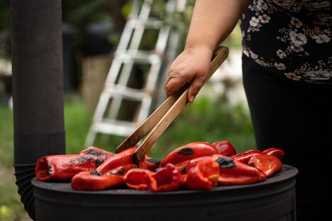 Žena peče papriku za ajvar na šporetu
