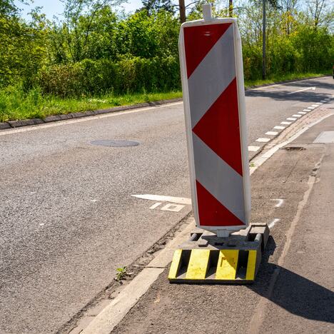 Crveno bela tabla sa dijagonalnim prugama koja označava prepreku pored puta