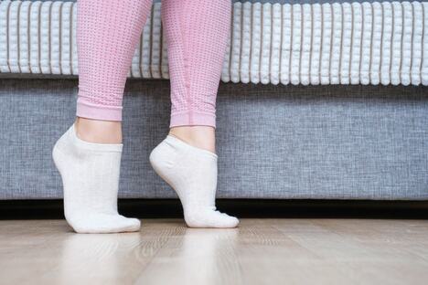podizanje na prste pored kreveta, u kadru noge mlade žene u roze helankama i belim soknama