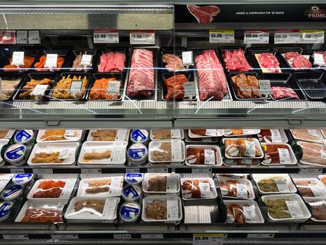 Sveže meso u crnim, žutim, belim i crvenim tacnama u supermarketu, različite boje ambalaže