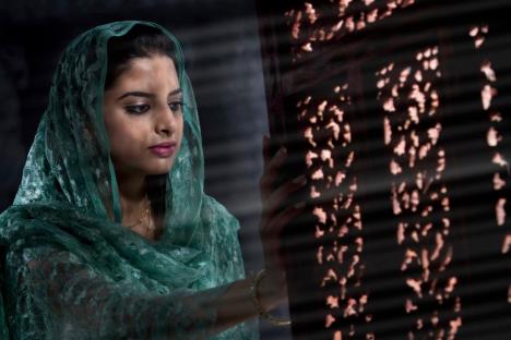 Muslimanka stoji kraj zamračenog prozora