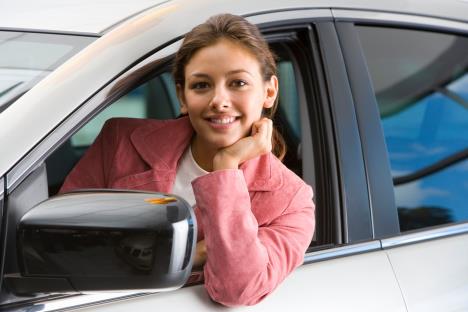 Nasmejana žena naslonjena na otvoren prozor auta