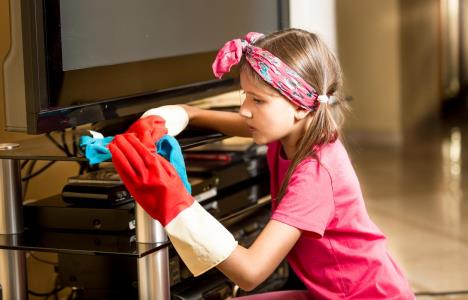 Devojcica u rozoj majici briše prašinu oko televizora