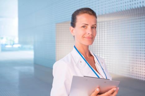 Doktorka stoji ispred bolnice sa fasciklom u ruci