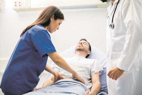 stockphotoprettyfemaledoctorinscrubstouchingtheabdomenofanunconsciouspatientintheemergencyroom533672728.jpg