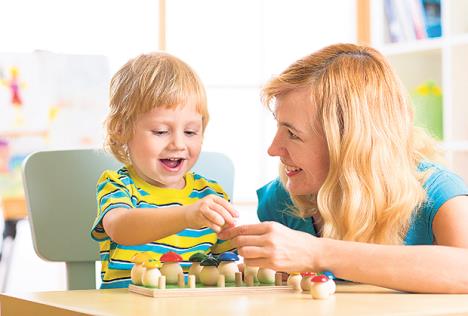 stockphotowomanandchildboytalkingandsmilingwhileplayingwitheducationaltoystogetherindaycare589299194.jpg