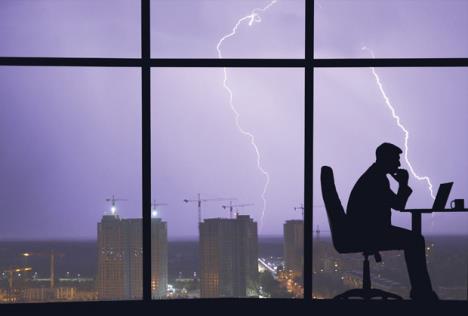 stockphotothemanworkingatthetablenearawindowonacitylightningbackground1460333147.jpg