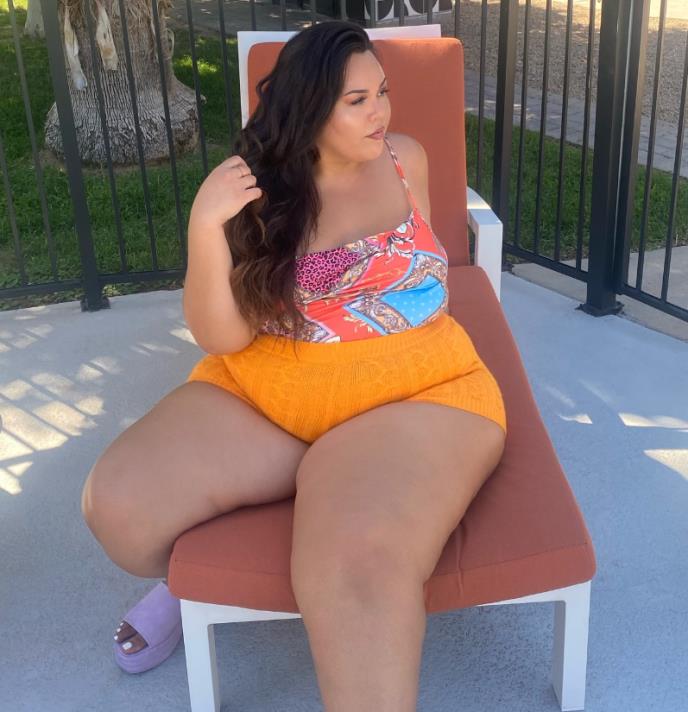 Džulija Sena u majici na bretele i narandžastom šortsu na stolici .jpg