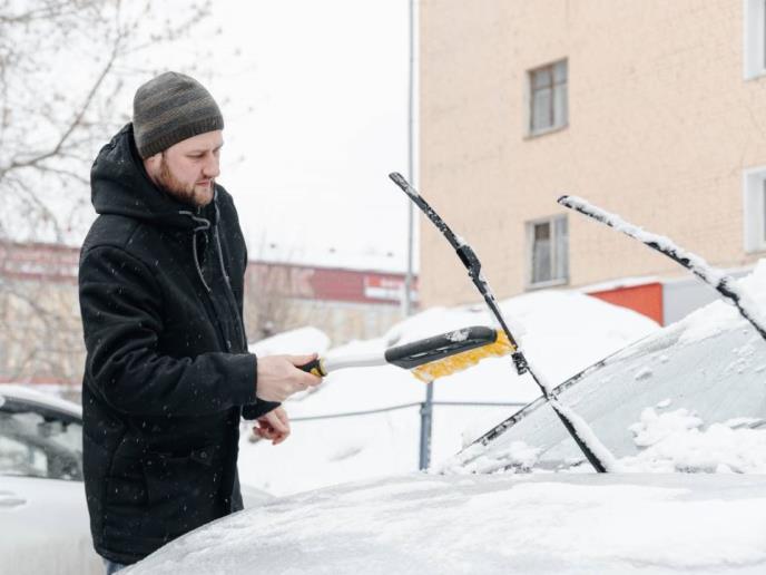 Čovek čisti podignute brisače od snega i leda
