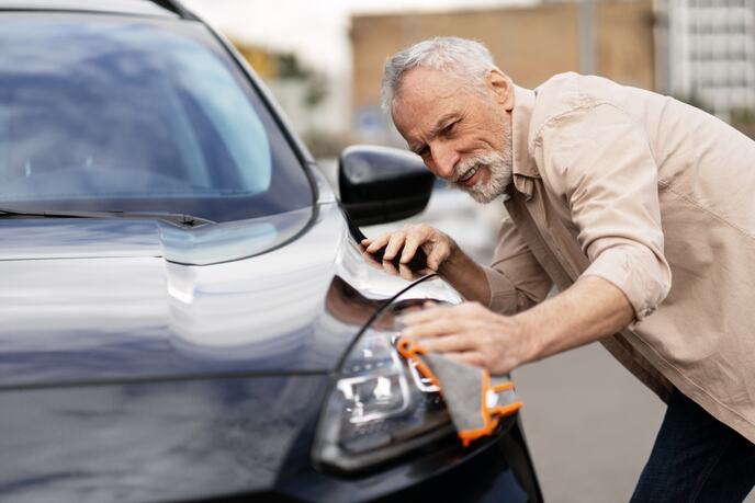 čovek čisti farove na automobilu